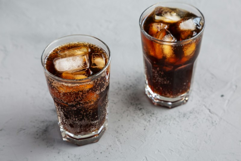 Cold Refreshing Dark Cola with Ice Cubes on a gray background, low angle view.